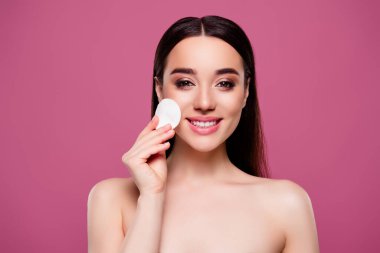 Pozitif kızın yüzü üzerinde pamuk sünger ile izole edilmiş pembe arkaplan fotoğrafı.