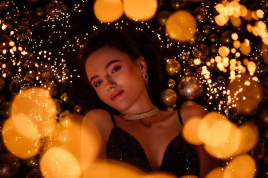 Topların arasında uzanan güzel lüks bir bayanın düz bir fotoğrafı. Yeni yılın sihirli atmosferinin tadını çıkar..