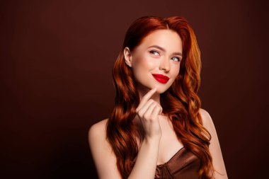 Kahverengi arka planda izole edilmiş boş bir reklam panosuna bakan güzel, hayalperest bir kadının fotoğrafı..