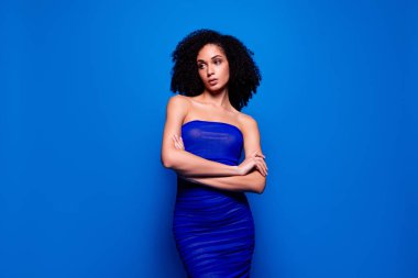 Ayakta duran kızın resmi gece elbisesi, çapraz el, profil kenarına bak, mavi arka plan..