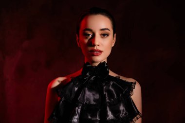 Çekici bir kızın portresi çekici görünüyor. Siyah gotik kıyafetler giyiyor..
