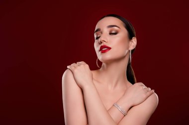 Çekici, genç ve güzel bir kadının fotoğrafı. Gözleri kapalı. Çıplak omuzlarına dokunuyor..