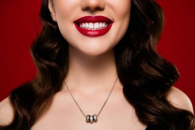 Kırmızı arka planda izole edilmiş değerli bir kolye takan çekici ve çekici bir kadının yakın plan fotoğrafı..