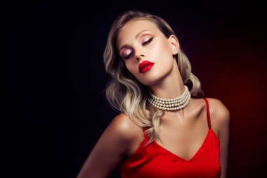 Çekici, güzel Hollywood yıldızının fotoğrafı koyu renk arka planda izole edilmiş kırmızı elbiseyle tutkuyla poz veriyor..