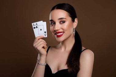 Poker kartları tutan muhteşem pozitif model kızın fotoğrafı haki renk arkaplanında izole edilmiş boş bir alan gibi görünüyor.