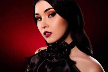 Kendine güvenen model kadının portresi koyu kırmızı arka planda izole edilmiş..