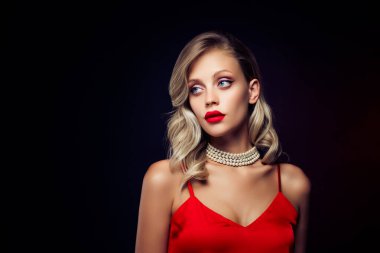 Çekici manken yıldızının fotoğrafı koyu renk arka planda izole edilmiş modaya uygun kırmızı elbise giyer.