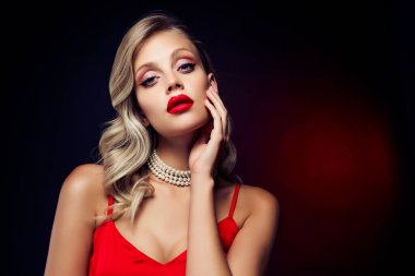 Çarpıcı muhteşem model dokunuşunun fotoğrafı koyu renk arkaplanda izole edilmiş yeni dekoratif kozmetiklerle karşılaşıyor.