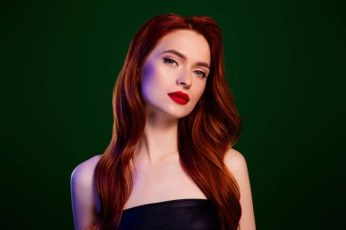 Havalı, güzel, kızıl saçlı bir kadının fotoğrafı. Özenle seçilmiş, koyu renkli bir arka plan..