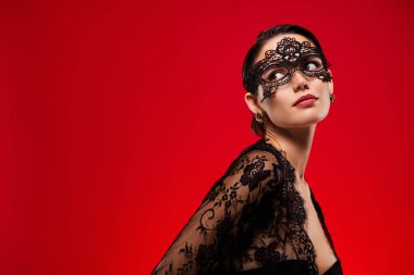 Göz kamaştırıcı seksi genç kızın fotoğrafı. Boş yere bak. Siyah elbise maskeli, cadılar bayramı partisinin kırmızı arka planı..