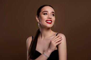 Tatlı tutkulu modelin fotoğrafı, siyah elbise giy. Lüks, boş, tenha, kahverengi arka planın tadını çıkar..