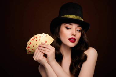Kahverengi arka planda izole bir şekilde poker oynayan çekici ve zengin bir kadının fotoğrafı..