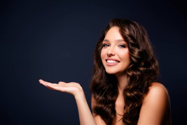 Şık ve göz kamaştırıcı, bu resim güzel ve zarif bir genç kadını çekici bir gülümseme ve koyu gri bir arka planda lüks saçla yakalıyor..