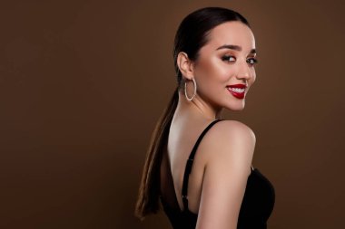 Tutkulu, parlak modelin fotoğrafı siyah elbise giy. Cazibeli kıyafetin tadını çıkar. Boş alan, izole edilmiş kahverengi arkaplan rengi..