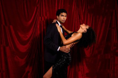 Şehvetli, çekici bir çiftin kırmızı kumaş arka planda VIP restoranında evlilik yıldönümünü kutlarken çekilmiş bir fotoğrafı..