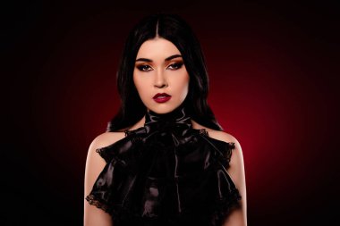 Kendine güvenen güzel bir kadının portresi koyu kırmızı arka planda siyah bir bluz..