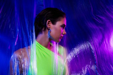 Muhteşem şık bir bayanın fotoğrafı şeffaf perdenin arkasında duruyor. Profiel tarafı izole edilmiş renkli arka plan..