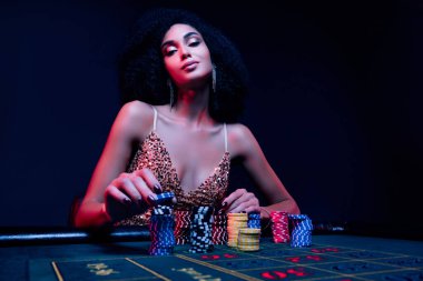 Gece poker kulübündeki şık bayanın fotoğrafı. Sinsi profesyonel oyuncu riskli bahis parası blöfü yapar..