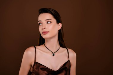 Kahverengi arka planda izole edilmiş, şenlikli etkinlikteki göz kamaştırıcı zarif hanımın fotoğrafı..