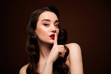 Çekici bir bayanın kahverengi arka planda izole edilmiş işaret sırlarını gösteren fotoğrafı..