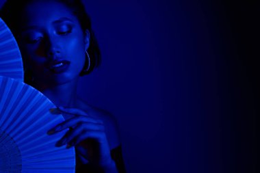 Japon kağıt fanatikleri tutan güzel bayanın kapalı gözleri. Boş uzay mavi arka planı..