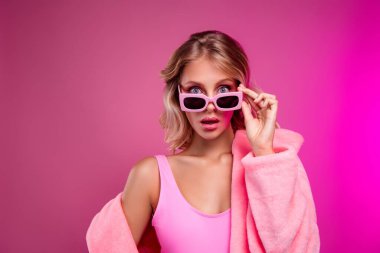 Çekici genç kadın modelin fotoğrafı güneş gözlüğü çıkarması hayret verici noel kürkü manto münferit pembe arka plan.