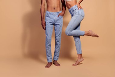 Bej bir arka planda kot pantolon giymiş çekici genç bir çift. Tarz ve modern modayı temsil ediyorlar. Aşk, güzellik ve doğal zarafet temaları için mükemmel..