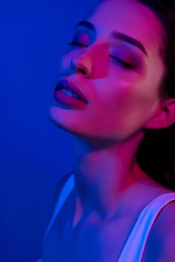 Güzel, çarpıcı bir bayanın fotoğrafı mavi arka planda kapalı gözlerle cezbedici geliyor..