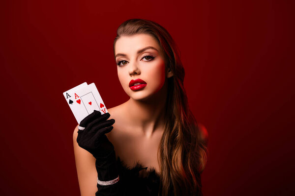 Photo of passionate lady dealer holding showing poker cards wear gloves feather gown on red color background.