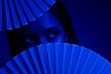 Çinli kadın kağıt fanatiklerinin fotoğrafı. Yüzünü kapatmış. Boş, koyu mavi arka plan..