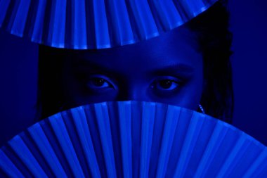 Güzel, parlak, kapalı gözlü bir kadının fotoğrafı Japon kağıt hayranları koyu mavi arka planda..