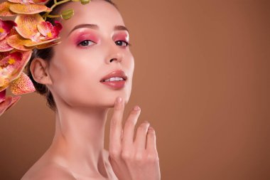 Rüya gibi baştan çıkarıcı kadının çıplak omuzlarının fotoğrafı orkide saç kozmetik ürünleri, izole edilmiş kahverengi arka plan..