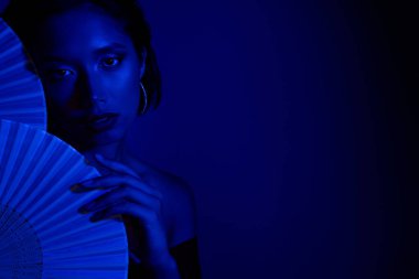 Çinli kağıt hayranlarının arkasına saklanan baştan çıkarıcı kadın boş alan mavisi arka plan.