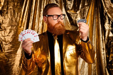Elinde poker fişleri ve kartları olan zarif bir beyefendi. Parlak, altın bir zemin hazırlıyor. Karizma ve entelektüellik saçıyor..