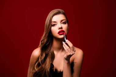 Çekici bir kadının fotoğrafı kırmızı arka planda ruj sürerken şehvetli hisseder..