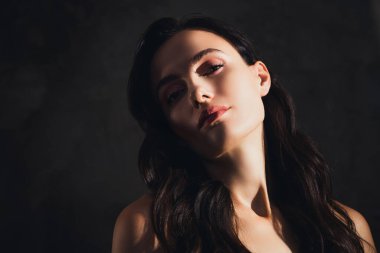 Şık bir bayanın gün ışığında koyu renkli arka planda flört ederken çekilmiş bir fotoğrafı..