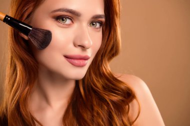 Güzel, çekici bir bayanın fotoğrafı. Bej rengi arka planda izole edilmiş çıplak fırça tozu kullan..