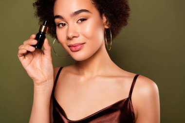 Çekici bir bayanın fotoğrafı haki rengi arka planda izole edilmiş nemlendirici serum içeriyor..