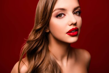 Parlak makyajlı, kıvırcık kahverengi saçlı, kırmızı arkaplanlı güzel bir bayan fotoğrafı..