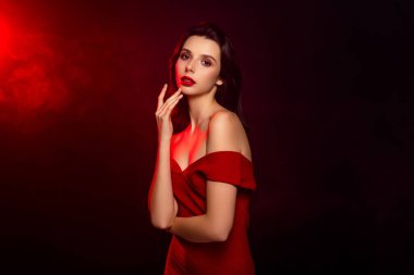 Zarif kırmızı elbiseli güzel bir esmer, gösterişli bir tarzı, entelektüel ve çekici bir görünüşü var. Yumuşak ışıklandırmalı kapkara bir arka plana karşı modaya uygun bir portre..