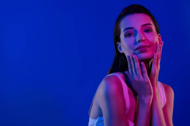 Güzel estetik bayanın fotoğrafı mavi arka planda izole edilmiş yumuşak, taze bir terapinin keyfini çıkar..