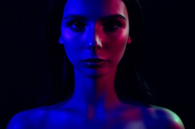 Dramatik mavi ve pembe neon ışıkla aydınlatılmış, modern sanatsal açıdan bir cazibe ve gizem hissi uyandıran genç bir kadının karanlık bir stüdyo portresi..