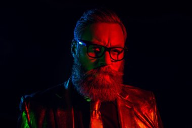 Parlak takım elbiseli karizmatik sakallı bir beyefendi, koyu bir arka plana karşı neon ışıklarıyla aydınlatılmış, geçmişe dönük bir cazibe ve zengin bir zarafeti somutlaştırıyor..
