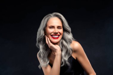 Siyah giysili zarif orta yaşlı kadın güzelliğini ve özgüvenini sergiliyor. Gri saçlı, ışıl ışıl gülümseyen, olgunluk, zarafet ve zarafet temalı şık ve göz kamaştırıcı..