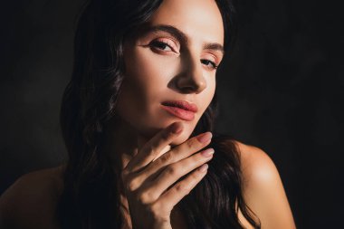 Güzel, şık bir bayanın fotoğrafı. Dokunaklı yüz çene. Güneşin altında, koyu renk arka plan üzerinde baştan çıkarıcı bir his..