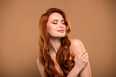 Çekici, çarpıcı bir kadının fotoğrafı yumuşak tene dokunur. Gözleri kapalı, omuzları çıplak, bej rengi arka planda izole..
