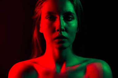 Koyu bir arka planda dramatik kırmızı ve yeşil neon ışıklarla aydınlatılan genç bir kadının sanatsal portresi modern ve şık bir estetiği sergiliyor..