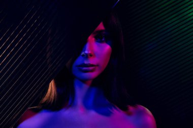 Büyüleyici bir sanatsal kompozisyon. Neon ışıklar altında genç bir kadın, harmanlanmış moda ve canlı renkler, gösterişli zarafet ve cazibe..