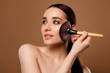 Güzel bir bayanın bej renkli arka planda izole edilmiş temel dekoratif makyaj uyguladığı fotoğraf..