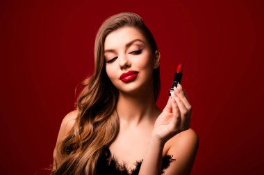 Şık kıvırcık saçlı bir kadının fotoğrafı. Kırmızı arka planda tüylü bir elbise giydiğini gösteren renkli dudaklar..